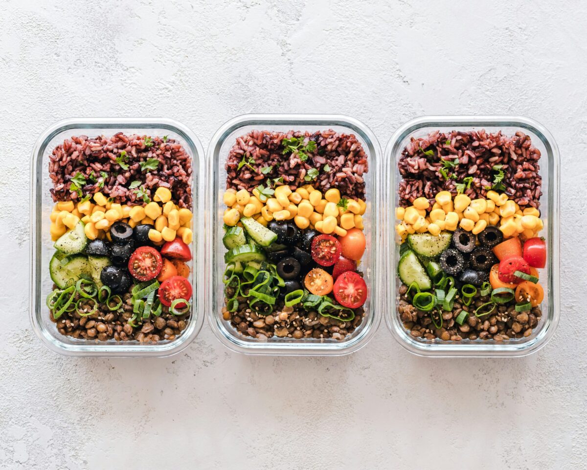 Three glass meal-prep bowls filled with rice, vegetables, and lentils